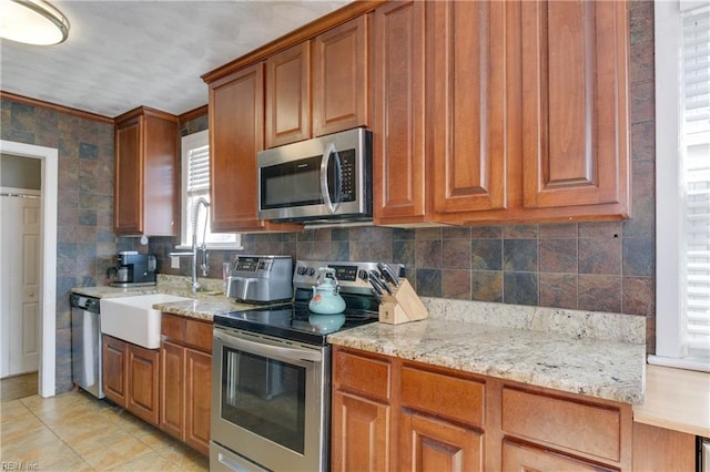 kitchen with light stone countertops, sink, decorative backsplash, light tile patterned flooring, and appliances with stainless steel finishes