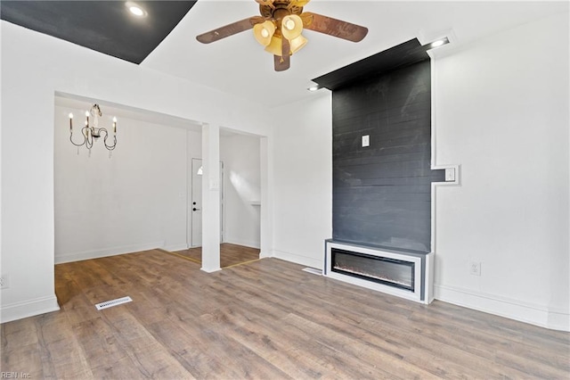 unfurnished living room featuring ceiling fan with notable chandelier and hardwood / wood-style flooring