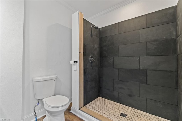 bathroom with a tile shower, tile patterned flooring, ornamental molding, and toilet