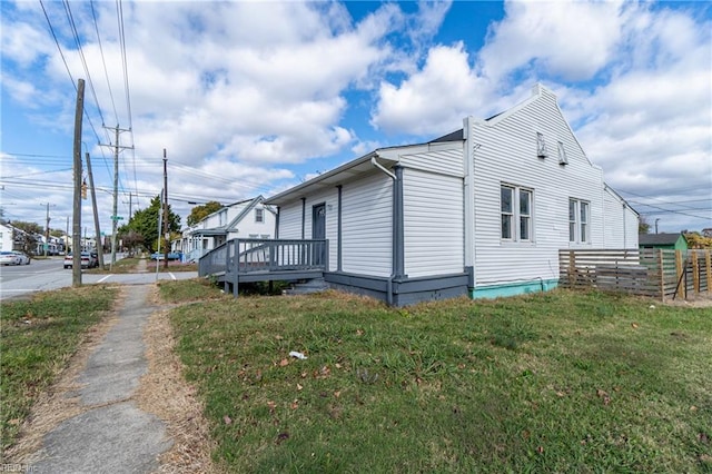 view of side of property with a lawn and a wooden deck