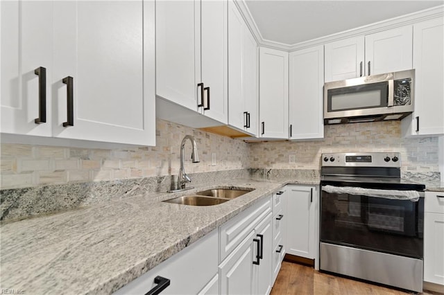 kitchen featuring white cabinetry, sink, light hardwood / wood-style floors, and appliances with stainless steel finishes