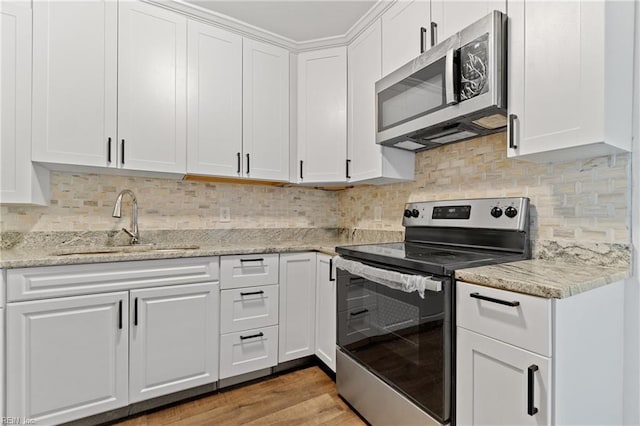 kitchen with backsplash, white cabinets, sink, light hardwood / wood-style flooring, and appliances with stainless steel finishes