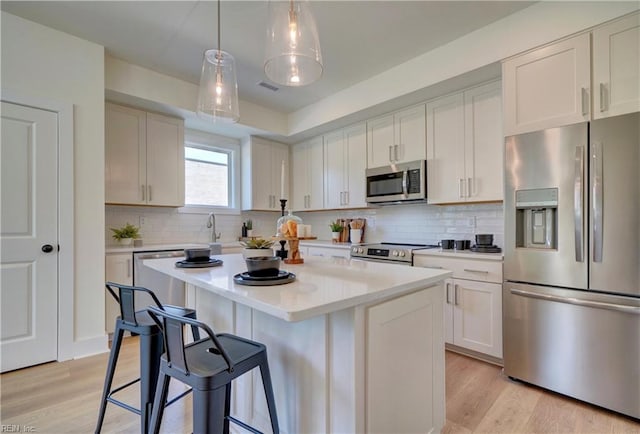 kitchen featuring a center island, white cabinets, stainless steel appliances, and light hardwood / wood-style flooring