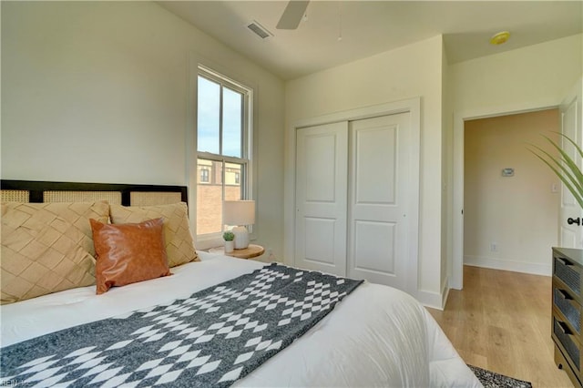 bedroom with a closet, light hardwood / wood-style flooring, and ceiling fan