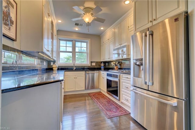 kitchen with dark hardwood / wood-style flooring, tasteful backsplash, stainless steel appliances, ceiling fan, and sink