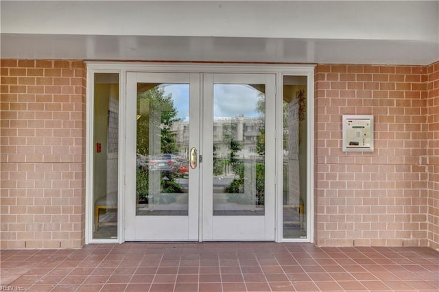 doorway to outside with tile patterned floors, brick wall, and french doors