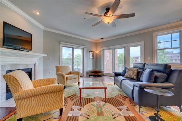 living room with light hardwood / wood-style floors, ceiling fan, crown molding, and a premium fireplace