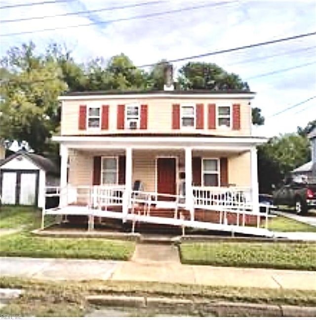 view of front of property featuring covered porch, an outdoor structure, and a front yard