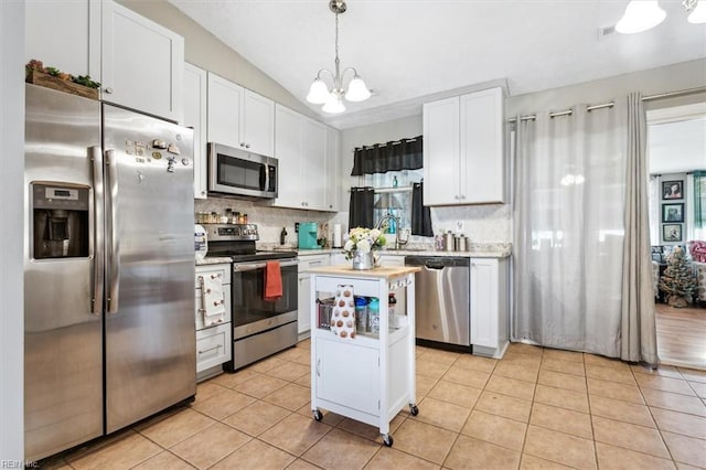 kitchen featuring white cabinets, hanging light fixtures, tasteful backsplash, a kitchen island, and stainless steel appliances