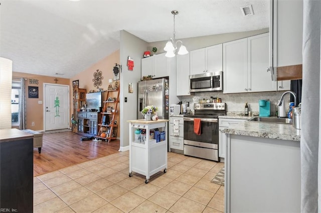 kitchen with white cabinets, appliances with stainless steel finishes, hanging light fixtures, and sink