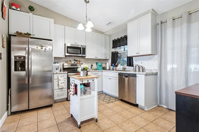 kitchen featuring stainless steel appliances, sink, pendant lighting, white cabinets, and lofted ceiling