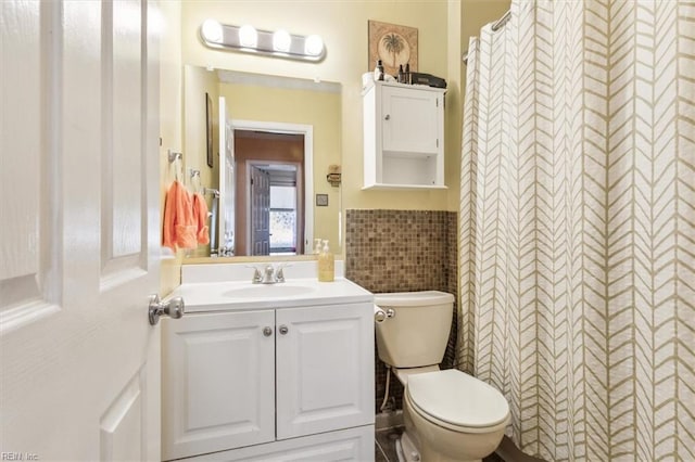 bathroom with vanity, toilet, and tile walls