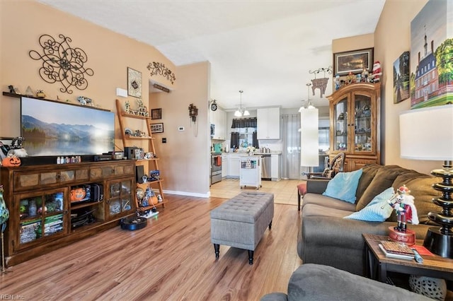 living room with a notable chandelier, light hardwood / wood-style floors, and vaulted ceiling