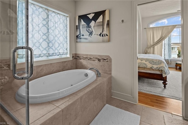 bathroom with hardwood / wood-style floors, plenty of natural light, and tiled tub