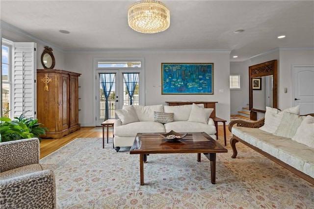 living room with french doors, an inviting chandelier, ornamental molding, and light wood-type flooring