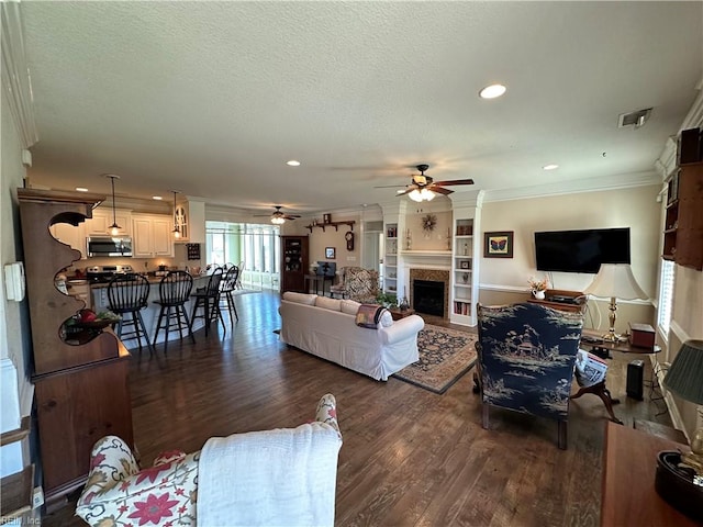 living room featuring ceiling fan, crown molding, dark wood-type flooring, and a textured ceiling