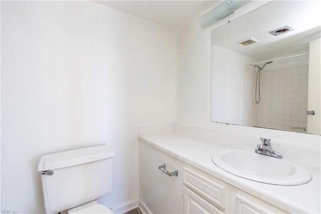 bathroom featuring a tile shower, vanity, and toilet