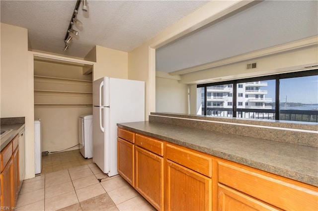 kitchen featuring track lighting, white refrigerator, a textured ceiling, and washing machine and clothes dryer