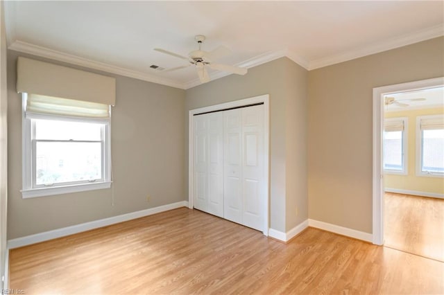 unfurnished bedroom featuring ceiling fan, a closet, ornamental molding, and light wood-type flooring