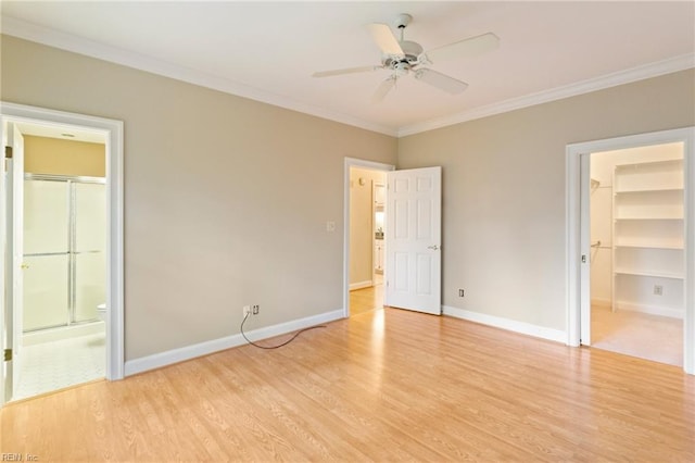 unfurnished bedroom with ensuite bathroom, ornamental molding, ceiling fan, a spacious closet, and light hardwood / wood-style floors