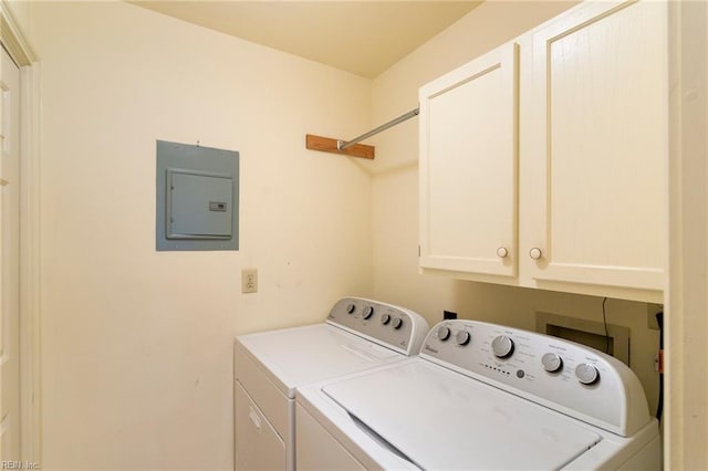 washroom with cabinets, washing machine and dryer, and electric panel