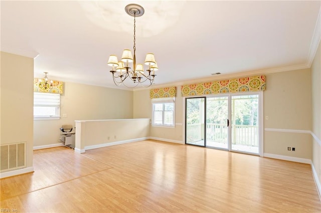 spare room with hardwood / wood-style flooring, plenty of natural light, and a chandelier