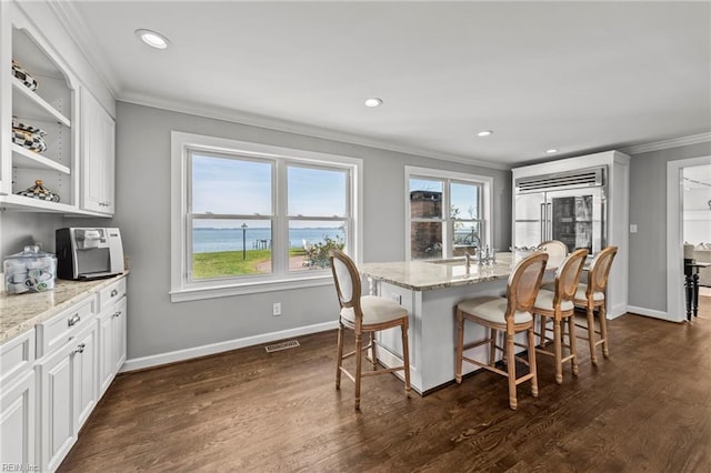 dining room with a water view, crown molding, dark wood-type flooring, and sink