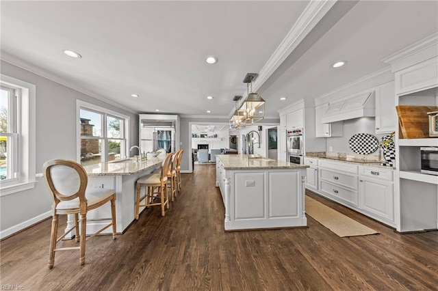 kitchen with sink, hanging light fixtures, dark hardwood / wood-style flooring, a spacious island, and white cabinets