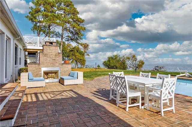 view of patio featuring a water view and exterior fireplace