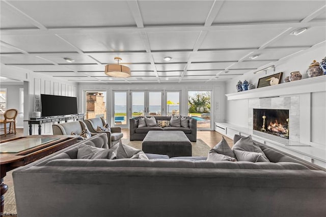 living room with a tile fireplace and coffered ceiling