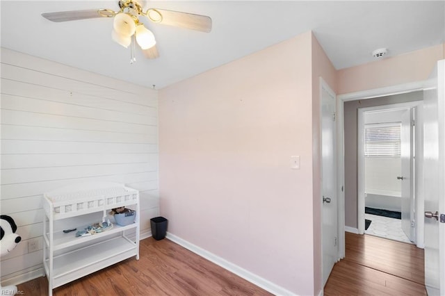 washroom featuring hardwood / wood-style floors, ceiling fan, and wood walls