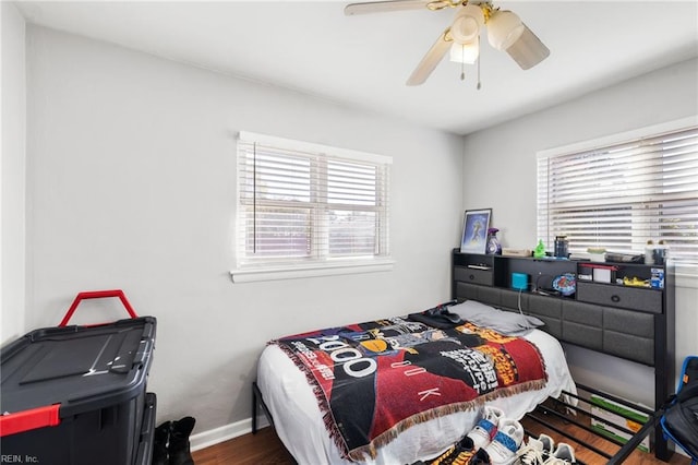 bedroom featuring ceiling fan, dark wood-type flooring, and multiple windows