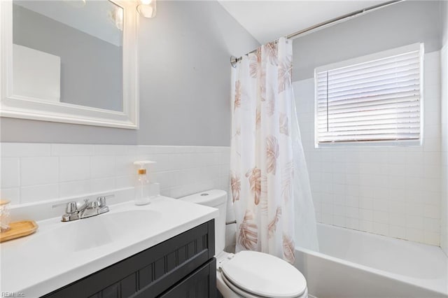 full bathroom featuring vanity, toilet, tile walls, and shower / tub combo