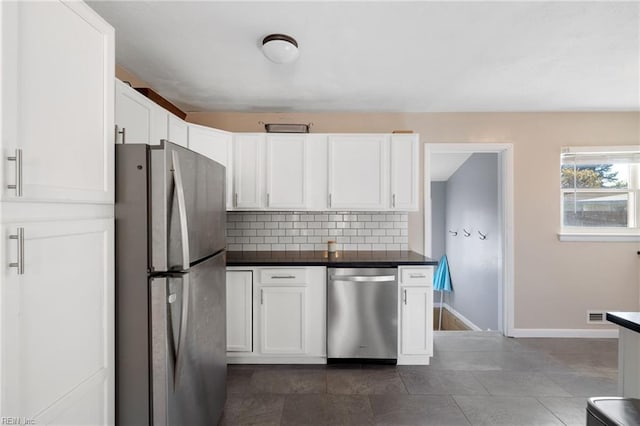 kitchen featuring dark tile patterned flooring, decorative backsplash, white cabinetry, and stainless steel appliances