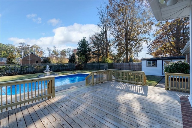 view of swimming pool with a storage shed and a wooden deck