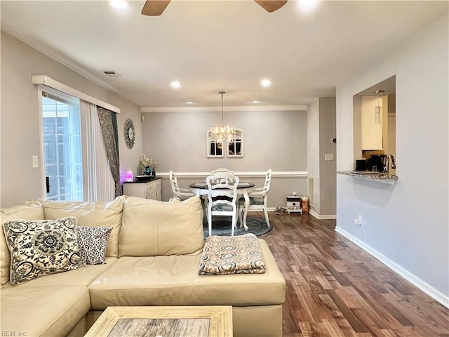 living room featuring crown molding, wood-type flooring, and ceiling fan with notable chandelier