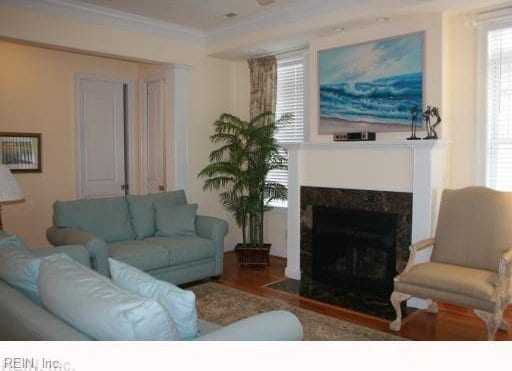 living room with hardwood / wood-style floors, a high end fireplace, and ornamental molding