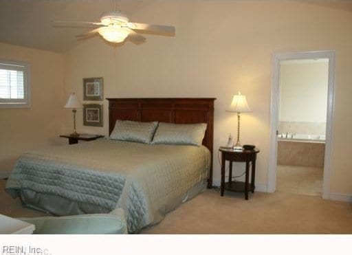 carpeted bedroom featuring ceiling fan, ensuite bathroom, and vaulted ceiling