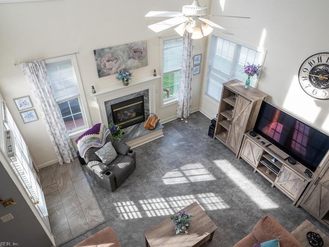 living room featuring a high end fireplace, a high ceiling, and ceiling fan