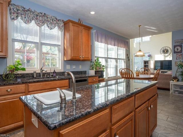 kitchen with dark stone countertops, sink, a kitchen island, and decorative light fixtures