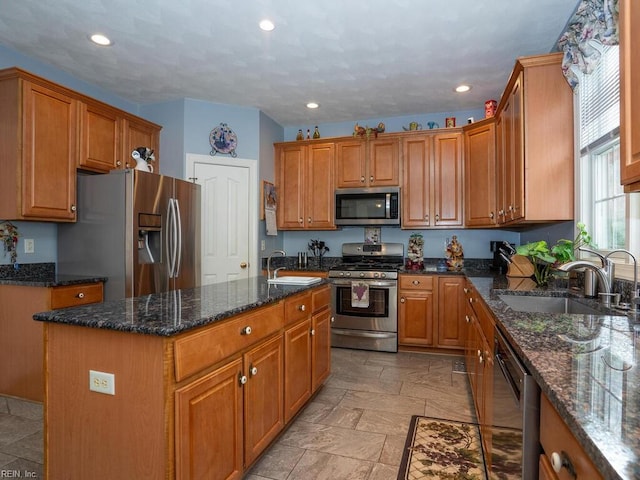 kitchen featuring a kitchen island, sink, appliances with stainless steel finishes, and dark stone counters