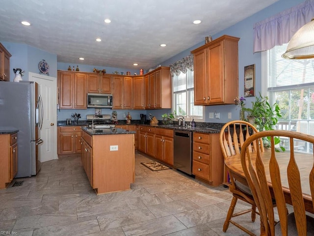 kitchen featuring sink, a kitchen island, dark stone counters, and appliances with stainless steel finishes