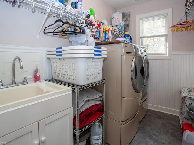 laundry area with dark tile patterned flooring, cabinets, independent washer and dryer, and sink