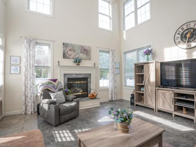 tiled living room featuring a healthy amount of sunlight, a towering ceiling, and a high end fireplace