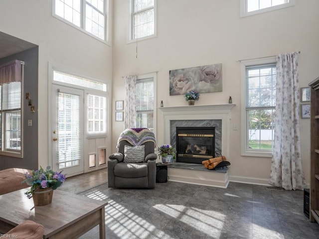 living room with a high end fireplace, a high ceiling, and a wealth of natural light