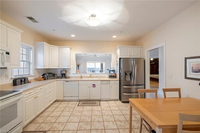 kitchen featuring white cabinetry, sink, white appliances, decorative backsplash, and light tile patterned floors