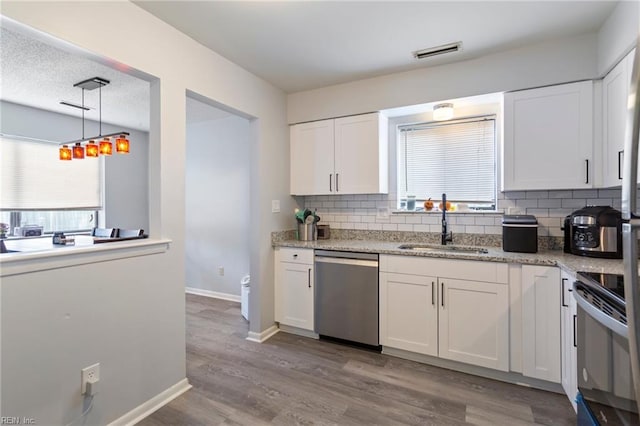 kitchen featuring white cabinets, tasteful backsplash, stainless steel appliances, and light hardwood / wood-style flooring