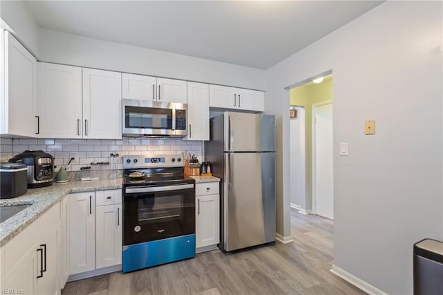 kitchen featuring white cabinets, backsplash, light wood-type flooring, and stainless steel appliances