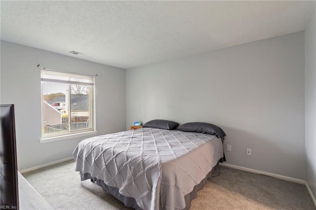 bedroom with light colored carpet and a textured ceiling