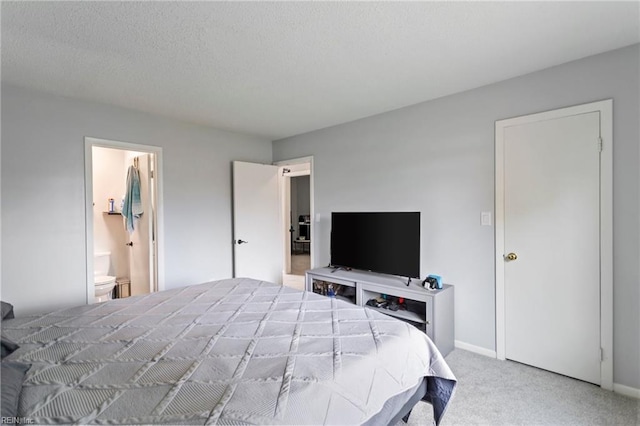 carpeted bedroom featuring a textured ceiling and connected bathroom